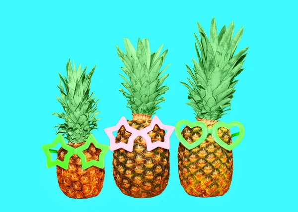 Tre ananas e occhiali da sole su sfondo blu, anan colorato — Foto Stock