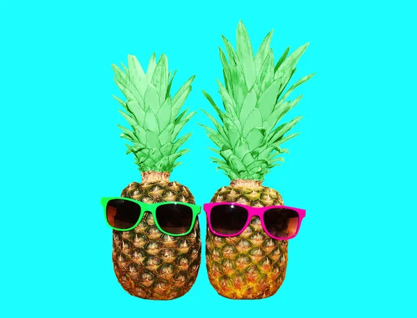 Due ananas con occhiali da sole su sfondo blu, anana colorata — Foto Stock