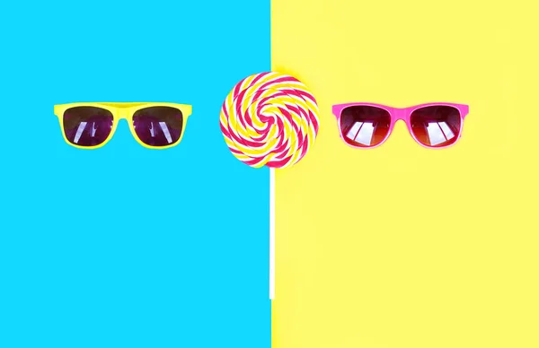 Two sunglasses and colorful lollipop caramel on stick over pink — Stock Photo, Image