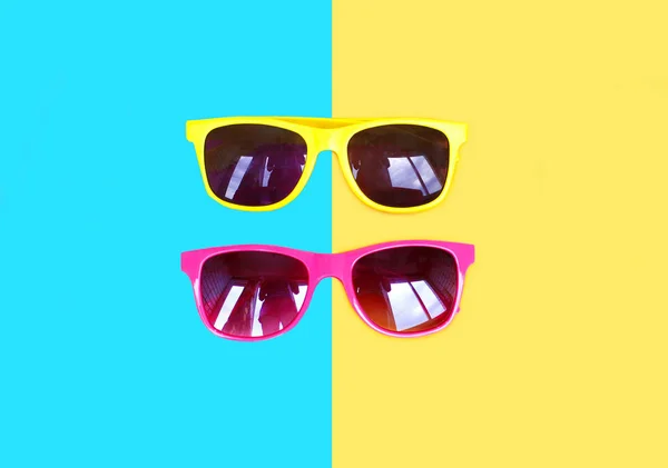 Dois óculos de sol amarelo rosa sobre um fundo colorido — Fotografia de Stock