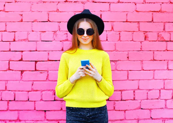 Moda menina legal usando smartphone sobre tijolo rosa colorido de volta — Fotografia de Stock