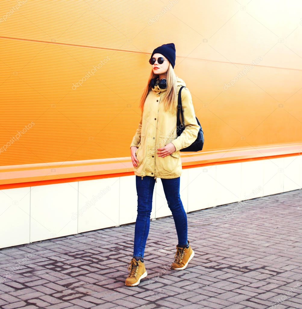 Fashion pretty blonde woman walking in city over orange colorful
