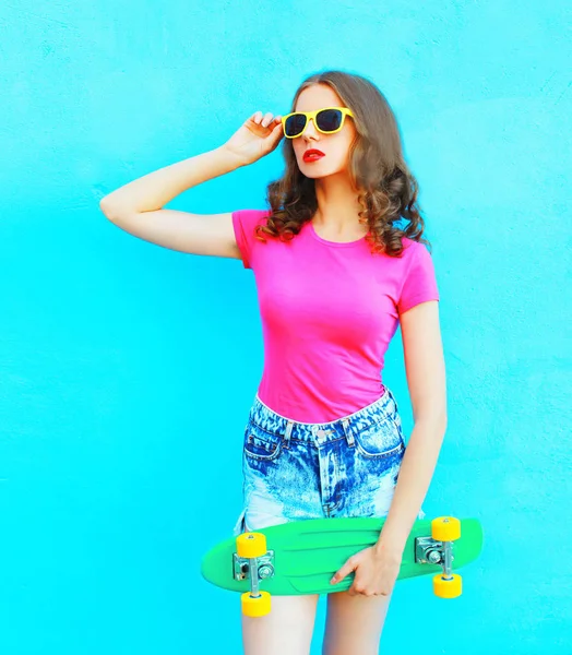 Moda bella donna tiene skateboard sopra colorato backgro blu — Foto Stock