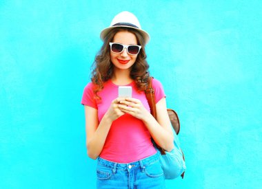 Hasır şapka ve bac smartphone kullanarak gülümseyen kadın moda
