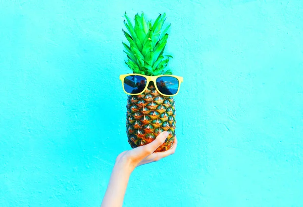 Мода ананас с солнцезащитными очками на синем фоне, руки холди — стоковое фото