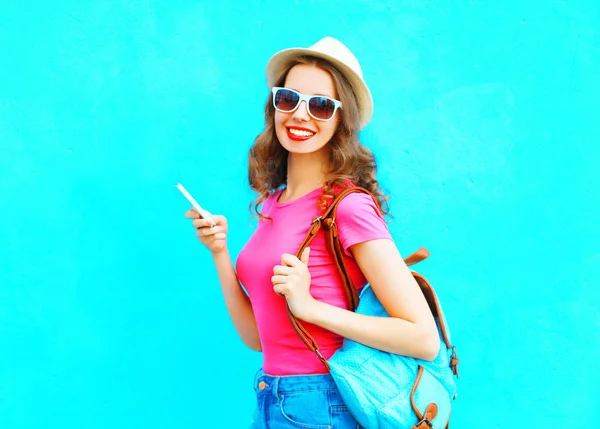 Uśmiechający się kobieta przy użyciu smartfona w mieście sobie słomkowy kapelusz moda — Zdjęcie stockowe