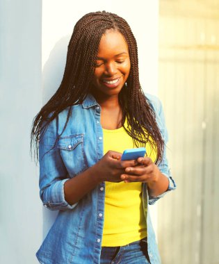 Moda mutlu gülümseyen Afrikalı kadın şehirde Smartphone kullanarak