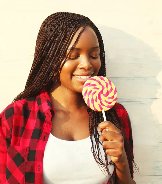 Beautiful happy smiling african woman is enjoying sweet lollipop