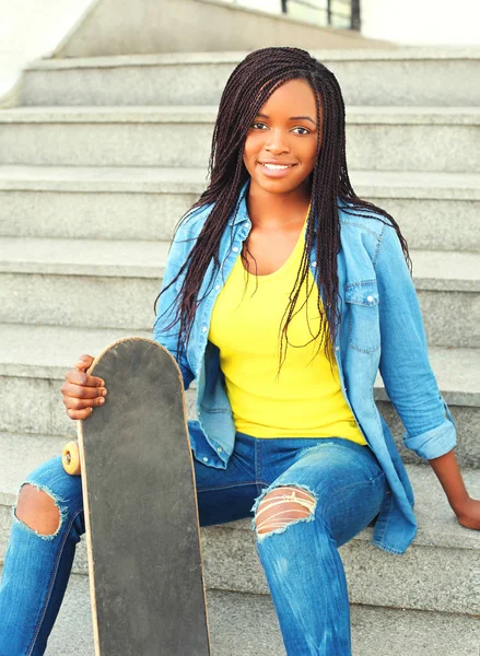 Mode vrij jonge Afrikaanse vrouw met skateboard zitten in een — Stockfoto