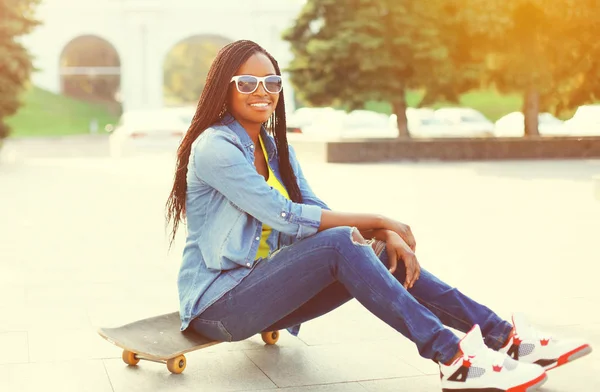 Mode ung afrikansk kvinna sitter på en skateboard i staden — Stockfoto