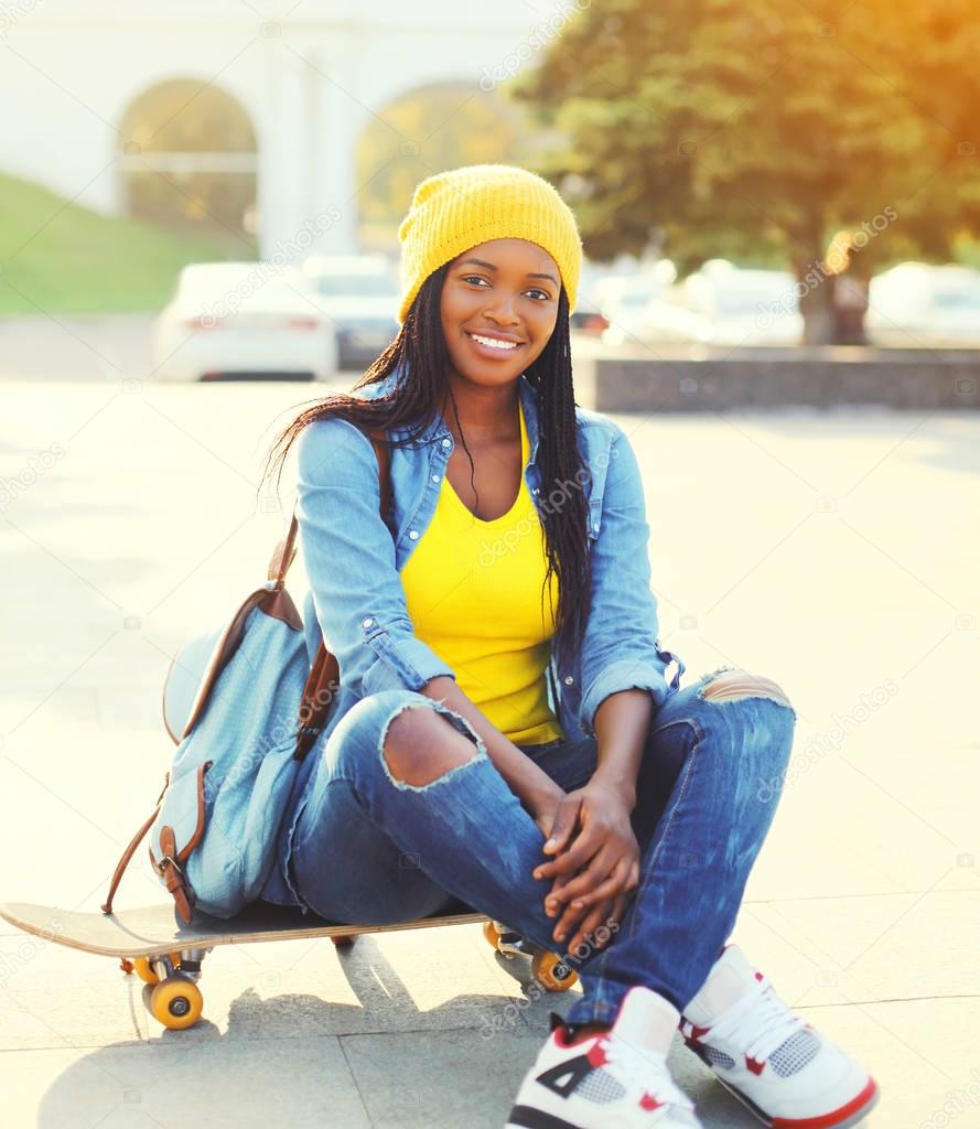 Fashion happy smiling young african woman with skateboard in the