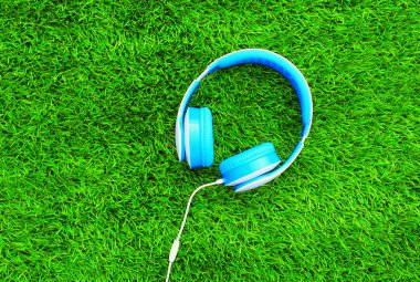 Mavi kulaklık yeşil dokulu bir arka plan üzerinde yalan