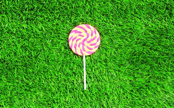 Colorido caramelo lollipop en palo sobre verde textura hierba bac — Foto de Stock