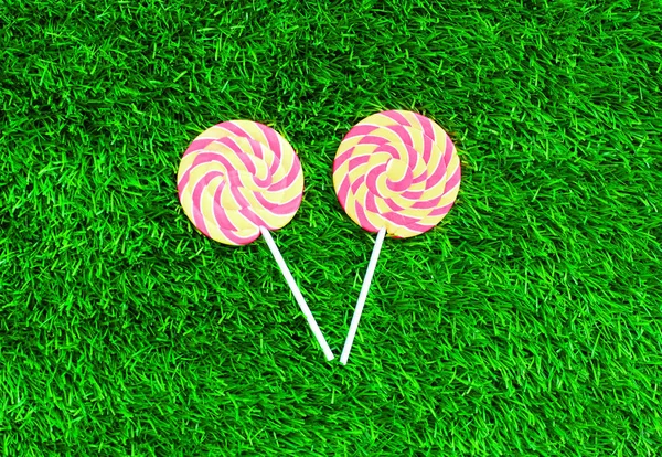 Two colorful lollipop caramel on stick over green textured grass — Stock Photo, Image