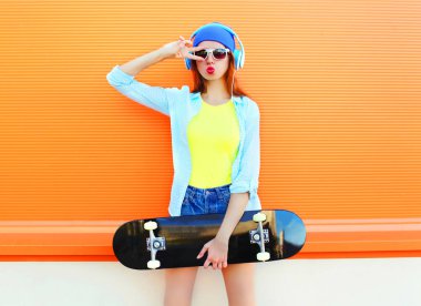 Bir kaykay ile kadın moda müzik üzerinde renkli o dinliyor.