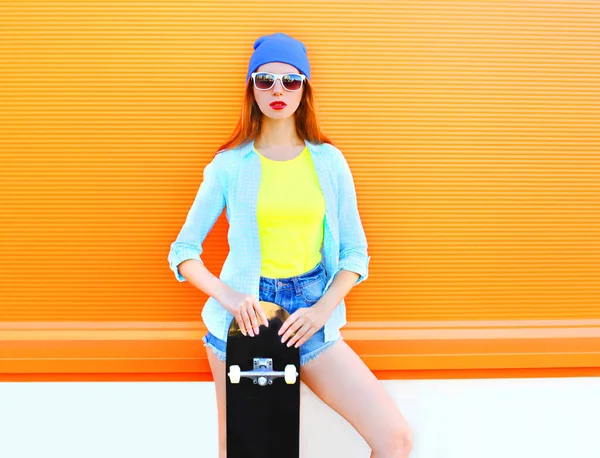 De mooie jonge vrouw mode met een skateboard in de stad over co — Stockfoto