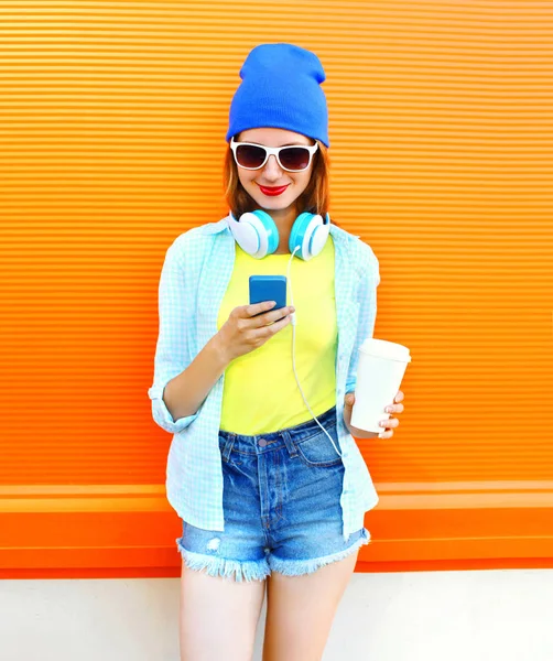 Moda sorridente giovane donna utilizzando smartphone con una tazza di caffè o — Foto Stock