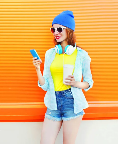 Moda sonriente mujer joven con una taza de café con teléfono inteligente o — Foto de Stock