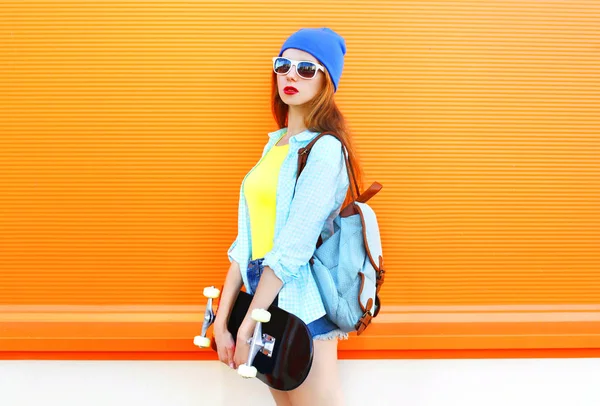 Moda jovem com um skate na cidade sobre colorido — Fotografia de Stock