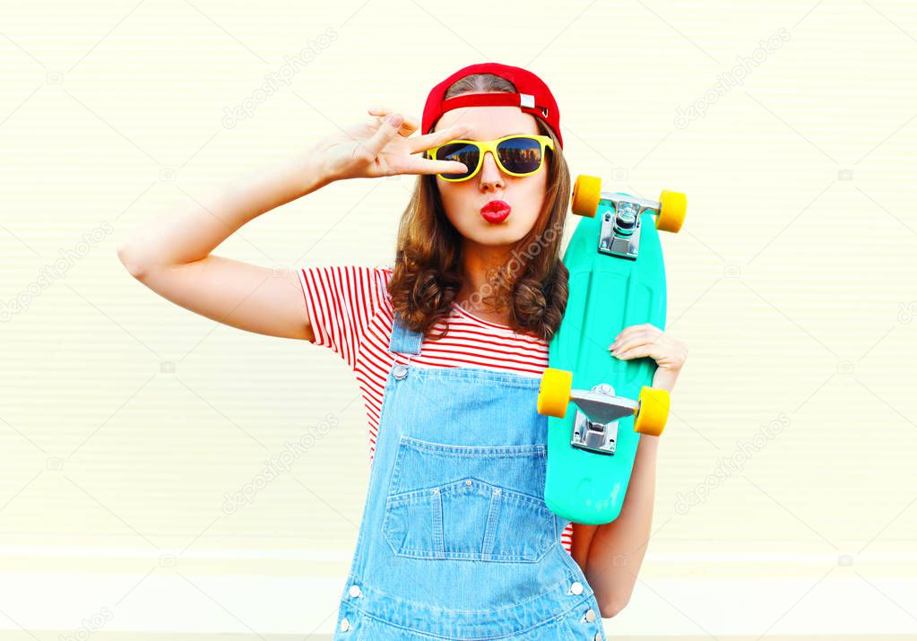 Fashion cool girl is pulling her lips with skateboard over white