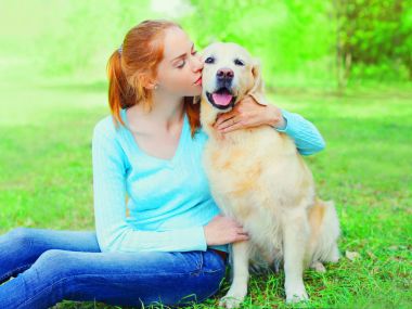 Mutlu sahibi kadınla çimenlerin üzerinde Golden Retriever köpek sarılma