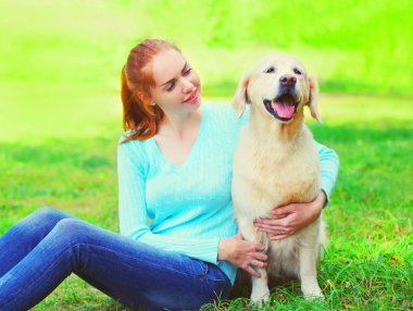 Mutlu sahibi kadın ve Golden Retriever köpek gülümseyen oturuyor