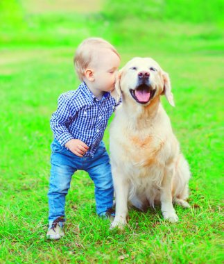 Küçük çocuk çocuk Golden Retriever köpek çim üzerinde öpüşme
