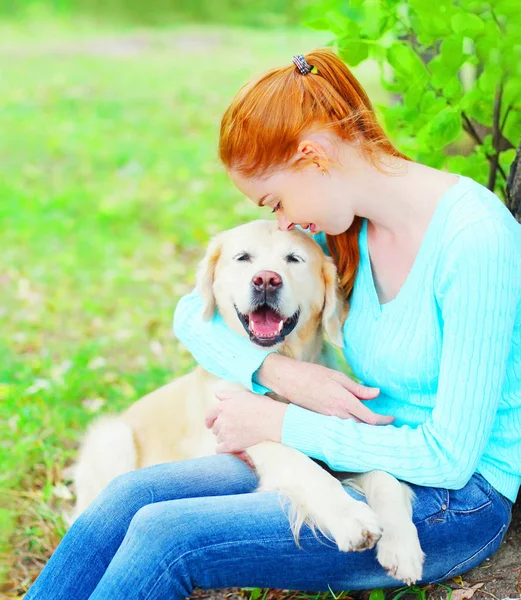 Счастливая хозяйка обнимает свою собаку-золотистого ретривера на гра — стоковое фото