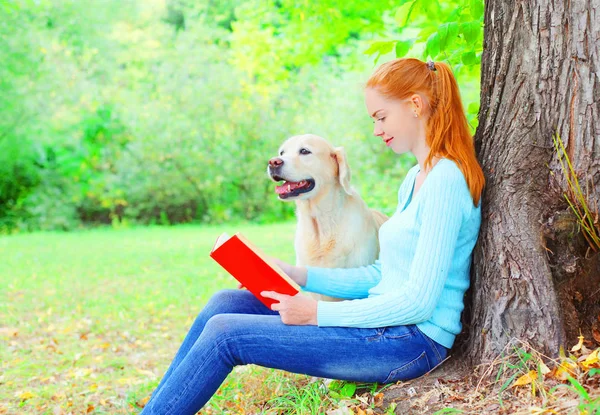 Счастливая хозяйка читает книгу с собакой золотого ретривера. — стоковое фото