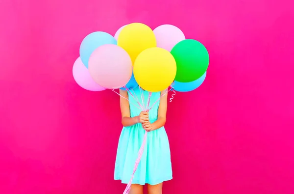 Женщина прячет голову воздушные разноцветные воздушные шары, веселясь над — стоковое фото