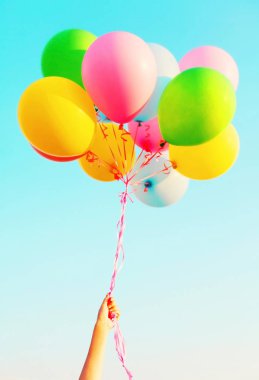 Hava balonları bir mavi gökyüzü backg üzerinde renkli bir demet el tutar