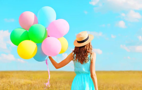 Bakifrån kvinna med en air färgglada ballonger i en stråhatt enj — Stockfoto