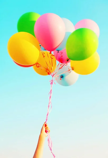 Χέρι κρατά ένα πολύχρωμο πακέτο αέρα μπαλόνια σε ένα καταγάλανο ουρανό backg — Φωτογραφία Αρχείου