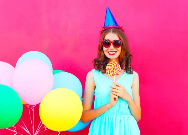 Glücklich lächelnde junge Frau in einer Geburtstagskappe mit einer Luft bunt — Stockfoto