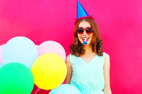 Gelukkige vrouw in een verjaardag-dop met een lucht kleurrijke ballonnen over — Stockfoto