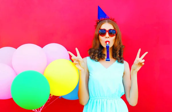 Glückliche junge Frau mit Geburtstagskappe in der Nähe eines Luftballons — Stockfoto
