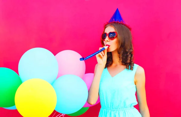 Glad ung kvinna i en födelsedag mössa med en färgglad luftballong — Stockfoto