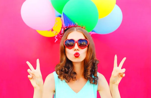 Mujer retrato en una gorra de cumpleaños está soplando los labios sostiene un aire co — Foto de Stock