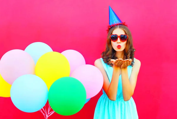 Bella donna con un cappello di compleanno è invia un bacio d'aria tiene un'aria — Foto Stock