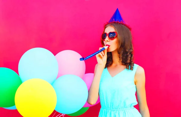 Mujer joven feliz en una gorra de cumpleaños con un globo colorido aire — Foto de Stock