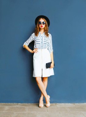 Bir çanta ile siyah şapka, beyaz etekli zarif kadın moda