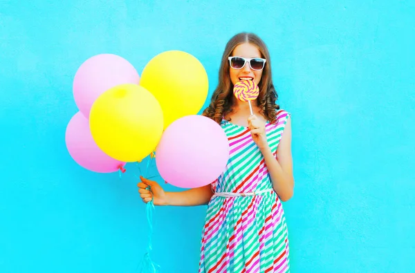 Mulher bonita com balões de ar morde um doce pirulito o — Fotografia de Stock