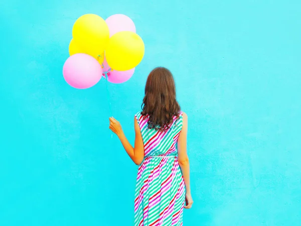 Mulher detém um ar balões coloridos em um fundo azul — Fotografia de Stock