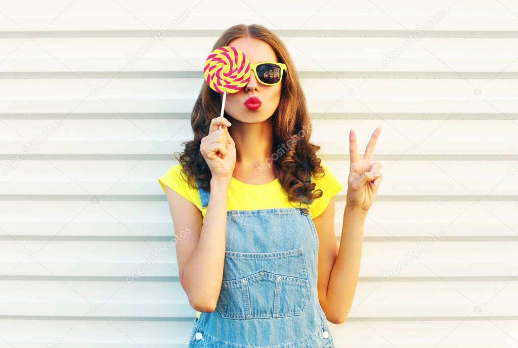 Fashion portrait woman holding a lollipops and blowing her lips 