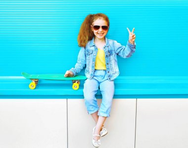 Moda üzerinde şehrin kaykay ile gülümseyen küçük kız çocuk bir