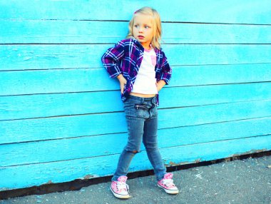 Küçük kız çocuk model üzerinde mavi bir ahşap backgrou poz moda