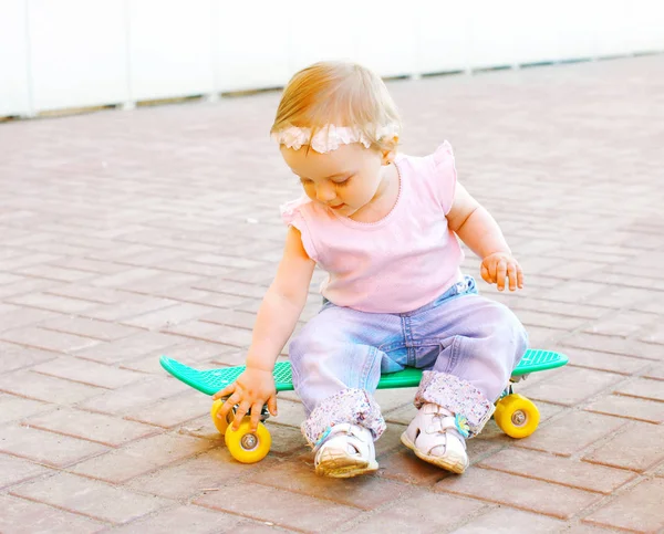 Дитина сидить на скейтборді в місті — стокове фото