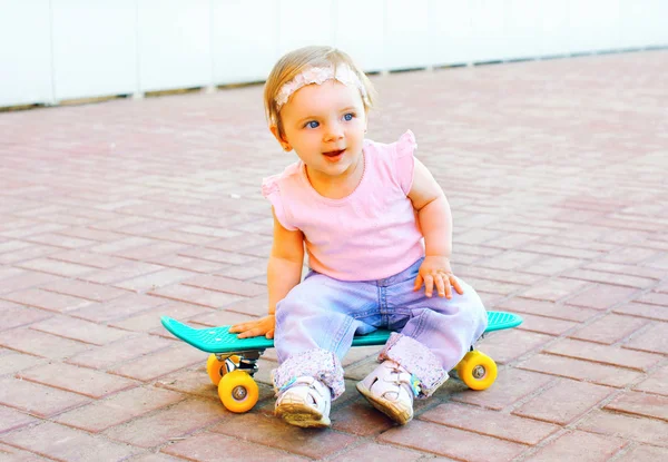 Engraçado bebê sentado no skate na cidade — Fotografia de Stock