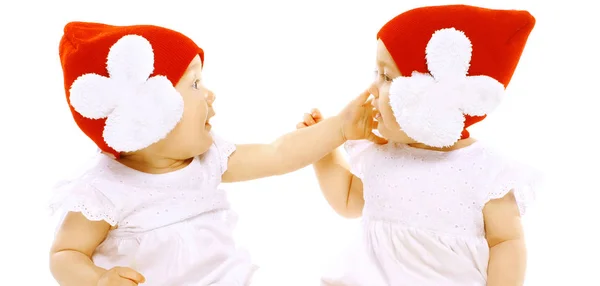 Closeup retrato dois bebês gêmeos em chapéus vermelhos cara a cara lutando — Fotografia de Stock