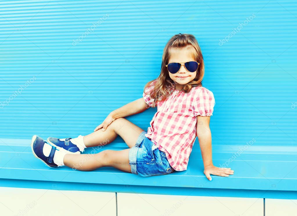 Fashion little girl child posing on a colorful blue background